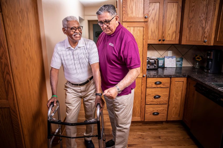Home Instead Caregiver assisting a senior client on walker at home