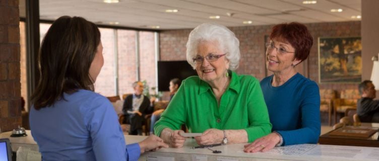 caregiver assisting senior check in a doctors appointment