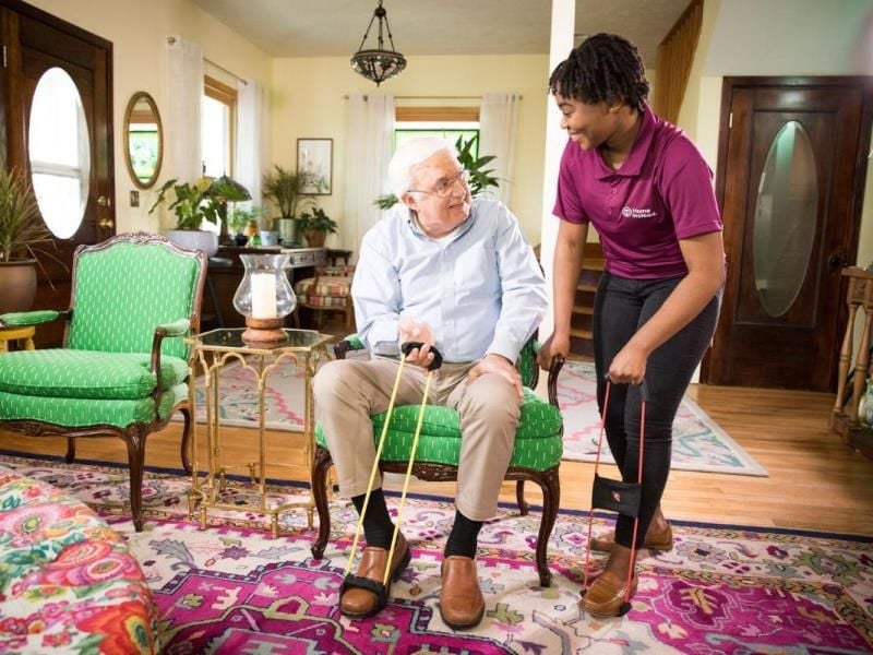 home instead caregiver cheerfully assists senior client transition to home care