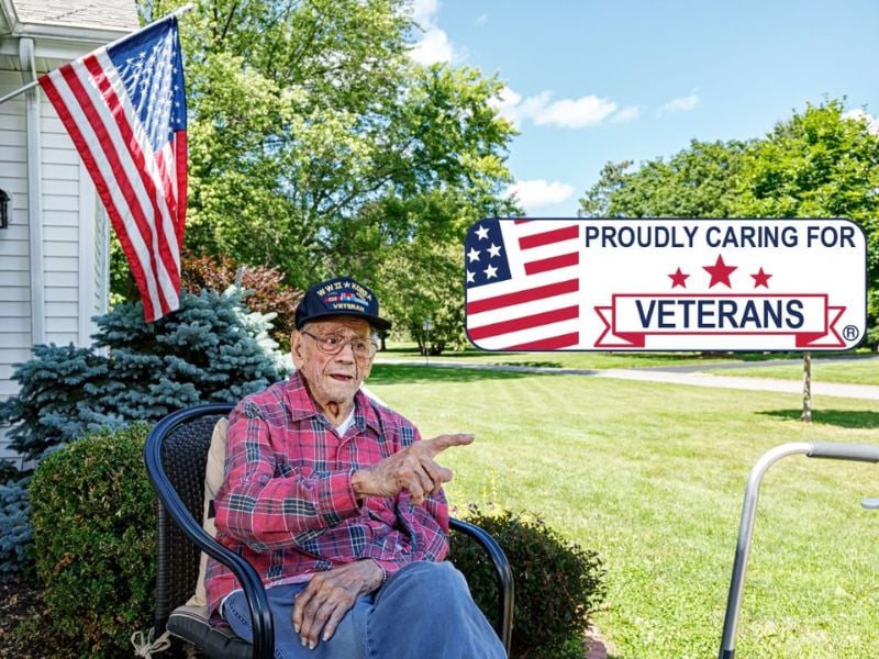 proud veteran sitting in front yard in his chair with US flag flying in background