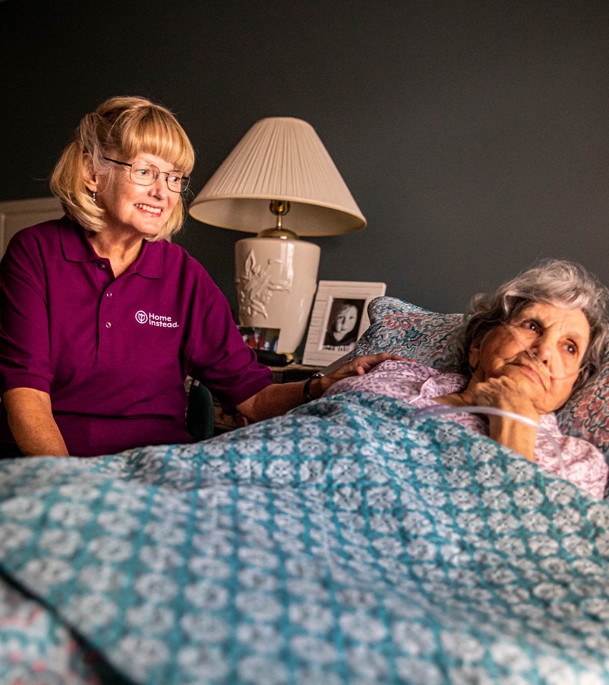 Home Instead CAREGiver sitting next to bed with senior