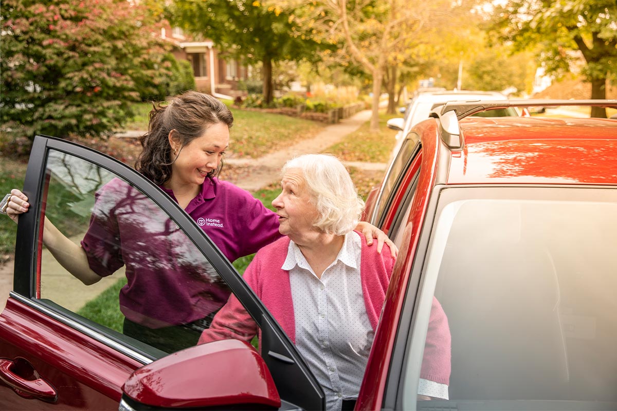 Home Instead Caregiver helps senior woman getting out of car