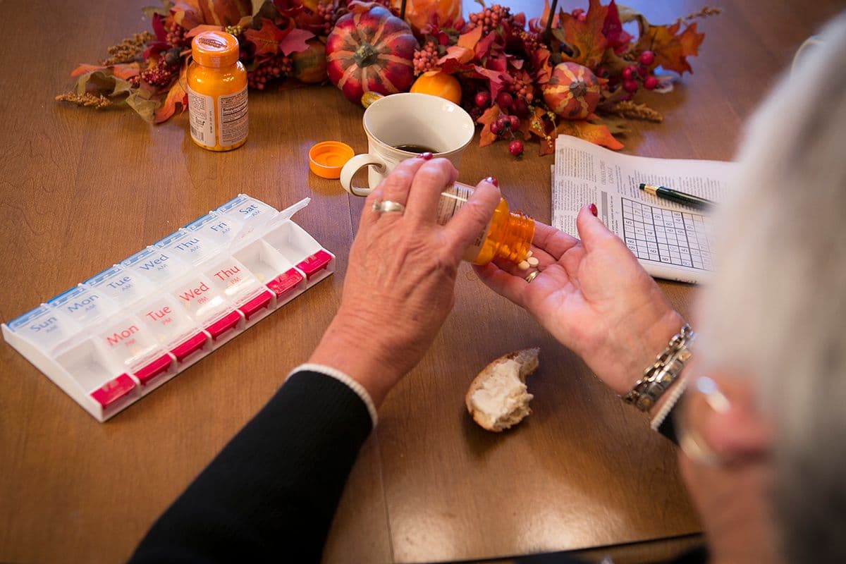 Senior pouring medication pills in to her hand