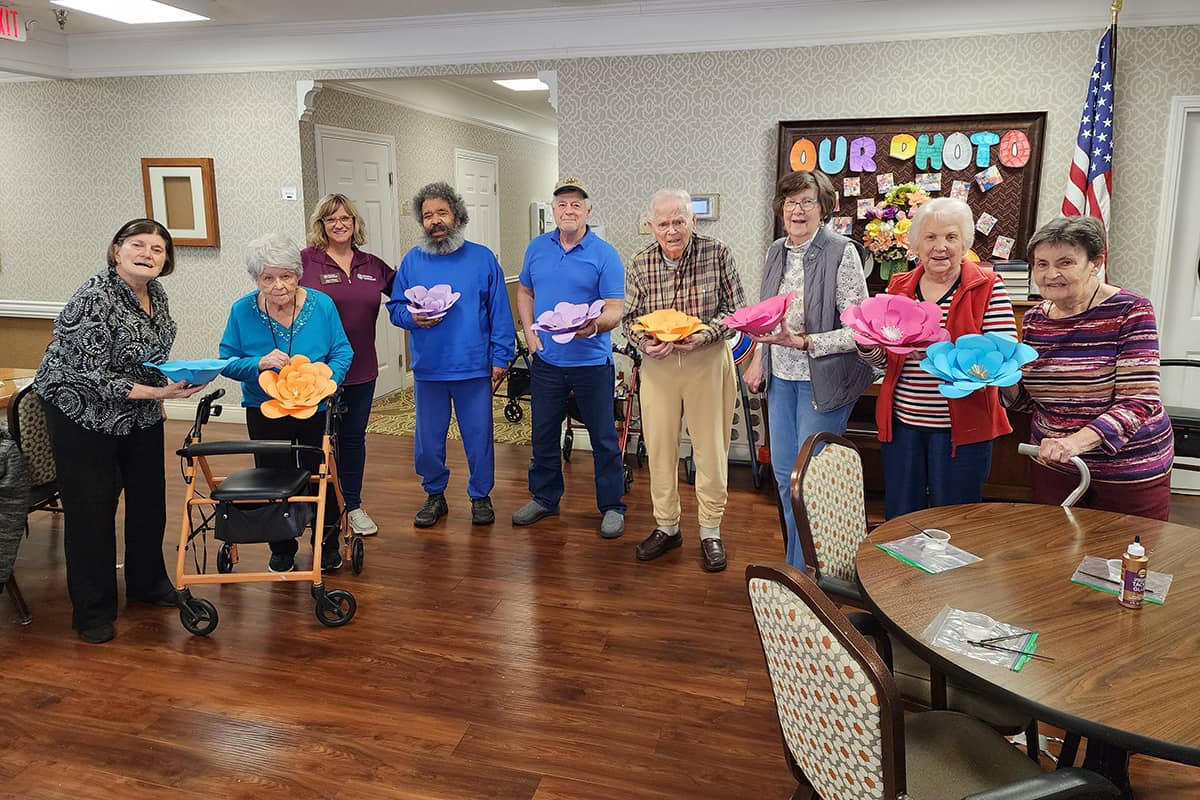 Photo of a Home Instead Care Professional and several seniors after having made paper wall flower decorations