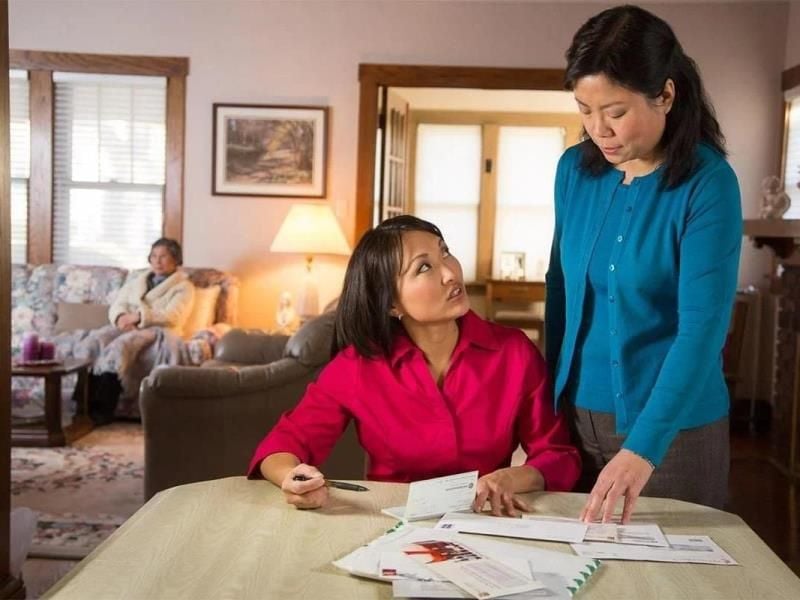 two ladies going over paperwork with senior sitting on the couch in the background