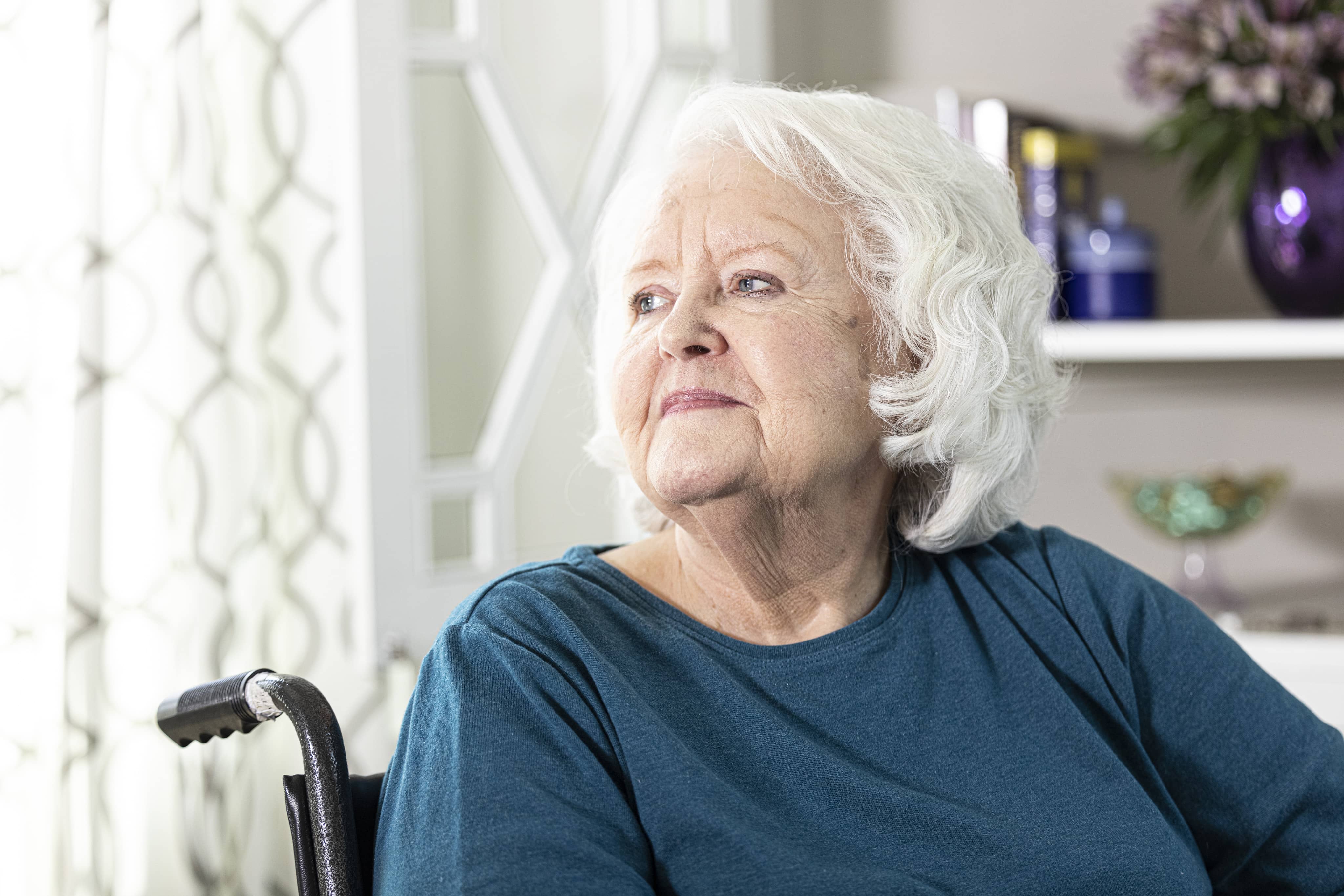 Senior sitting in a wheelchair by an open window