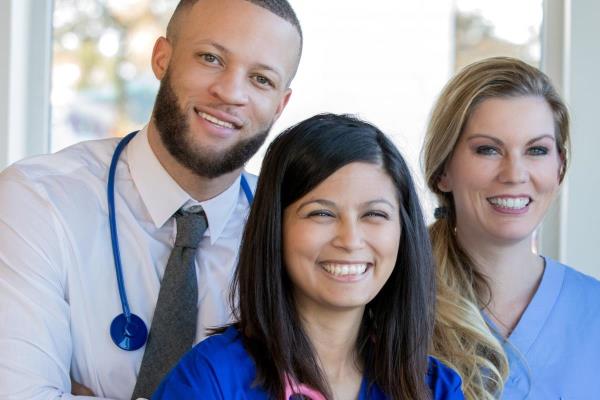 A team of healthcare professional smiles, representing the many career paths that professional caregiving can lead to.