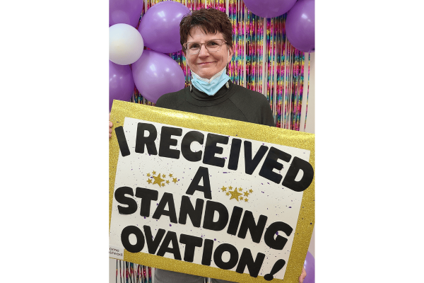 Photo of Care Professional, Susan, holding a sign that says, "I received a Standing Ovation."