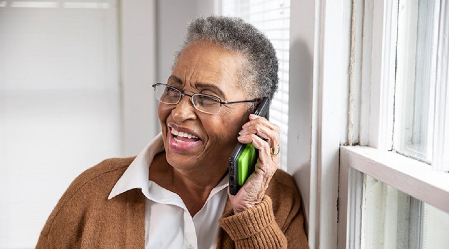 senior woman smiles while talking on mobile phone at home