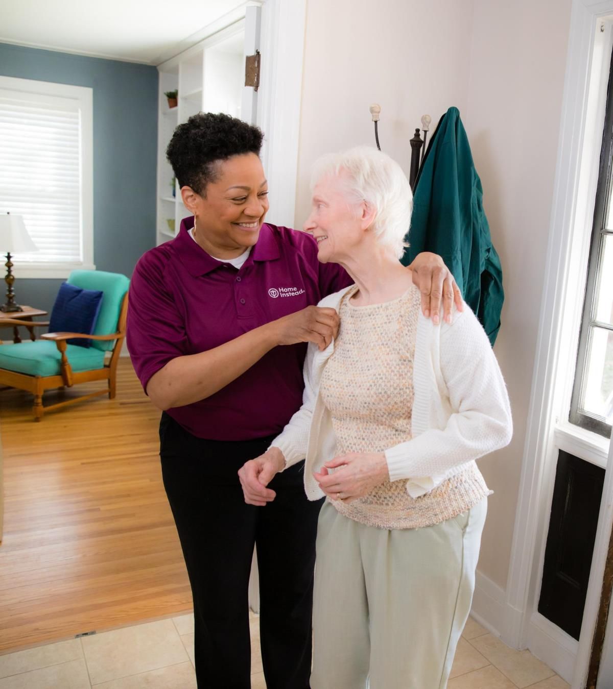 Home Instead Caregiver and senior client sharing a warm smile and side hug