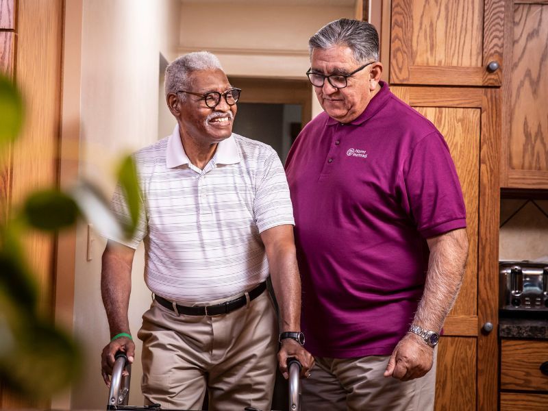 home instead caregiver assisting a senior on a walker at home