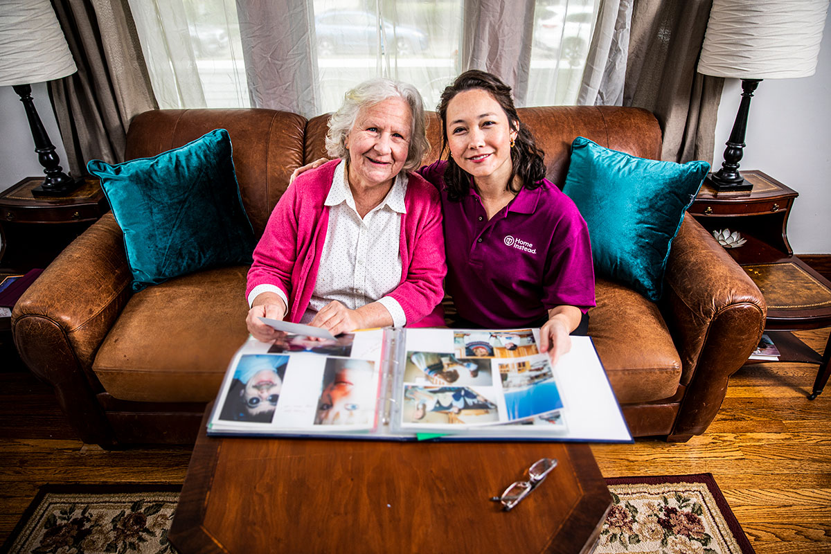 home instead caregiver looking through a photo book with elderly female client