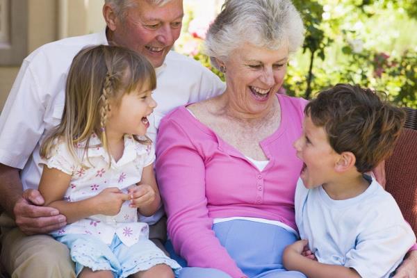 grandparents sat on a sofa laughing with grandchildren HtcAiHRri PMNW