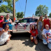 home instead seward, ne team posing at 4th of July parade with wrapped car