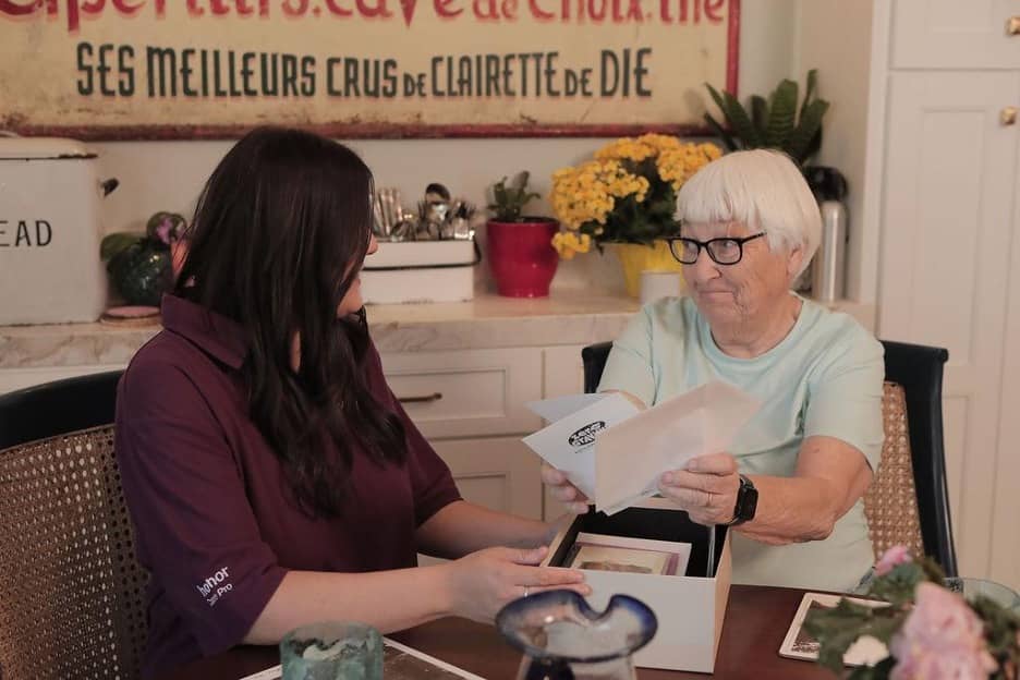 Photo of a Care Pro sitting at the kitchen table with her Dementia Care Client looking at pictures