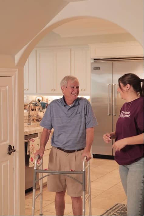 Senior with a walker and a Care Pro standing in archway between kitchen and another room (1).jpg