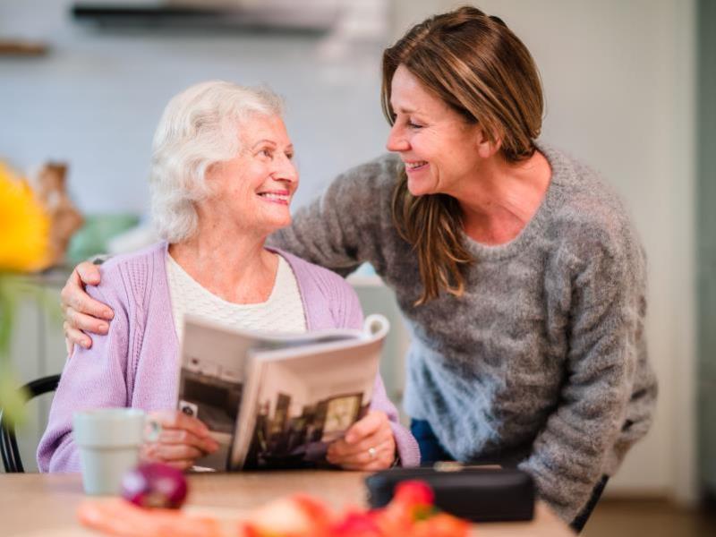 senior woman reads magazine caregiver looks over shoulder