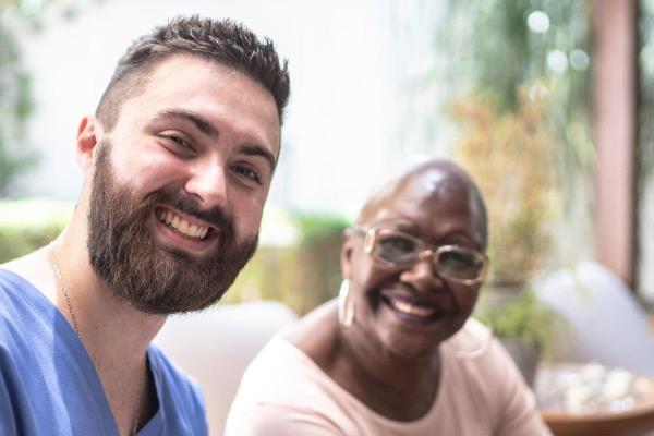 A man enjoys his caregiver job as he works with a client. 