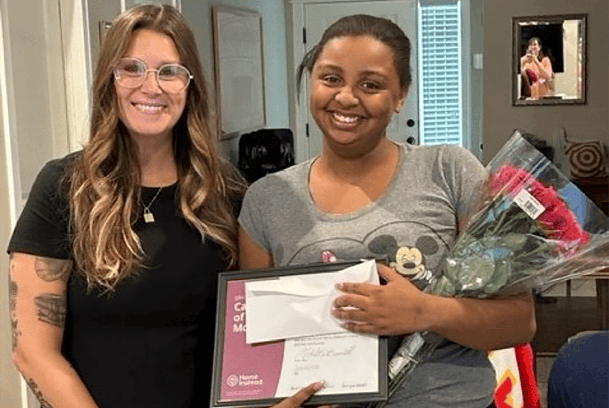 July Care Pro of the Month, Lyric receiving her certificate and flowers from Onboarding Assistant, Malorie