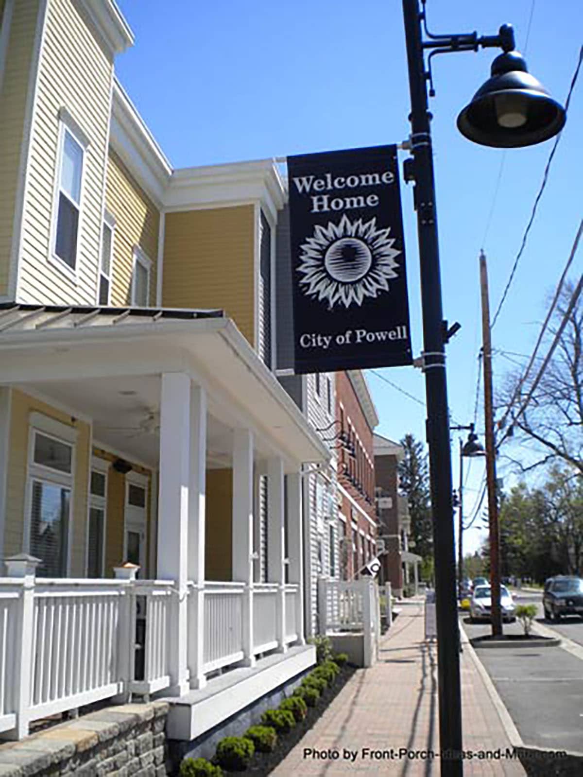 Photo of "Welcome Home City of Powell" light post banner in front of yellow house. 