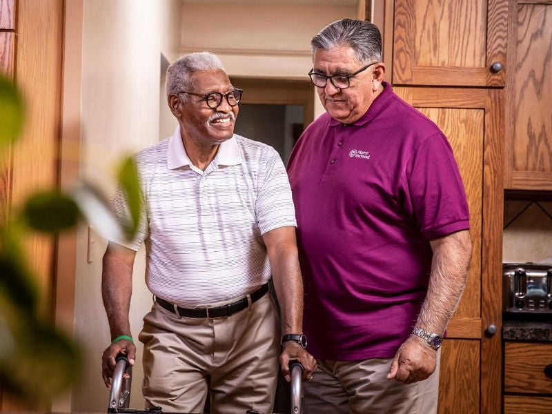 home instead caregiver walking alongside a senior on a walker at home