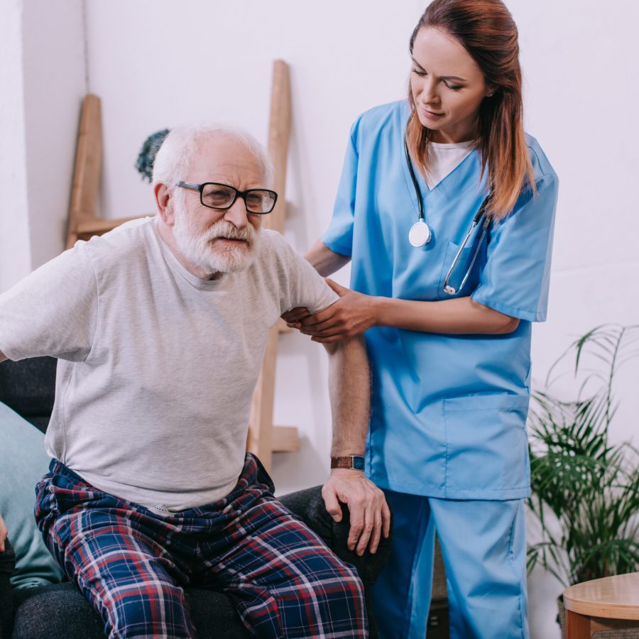 nurse helping old man to stand up from chair H2QUUQM scaled