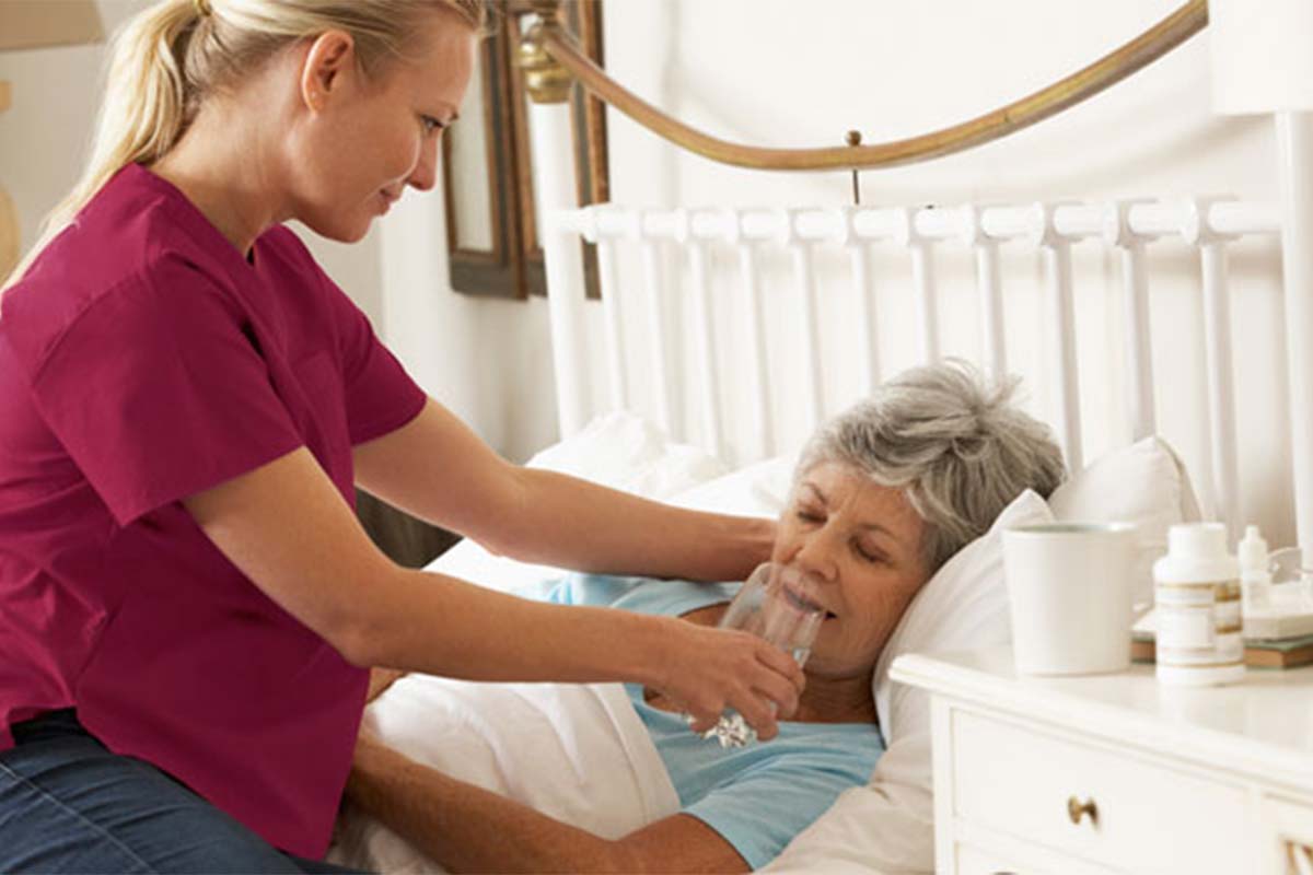 caregiver helping senior at her home with recovy from illnes