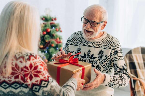 Caregiver giving a Christmas present to a senior