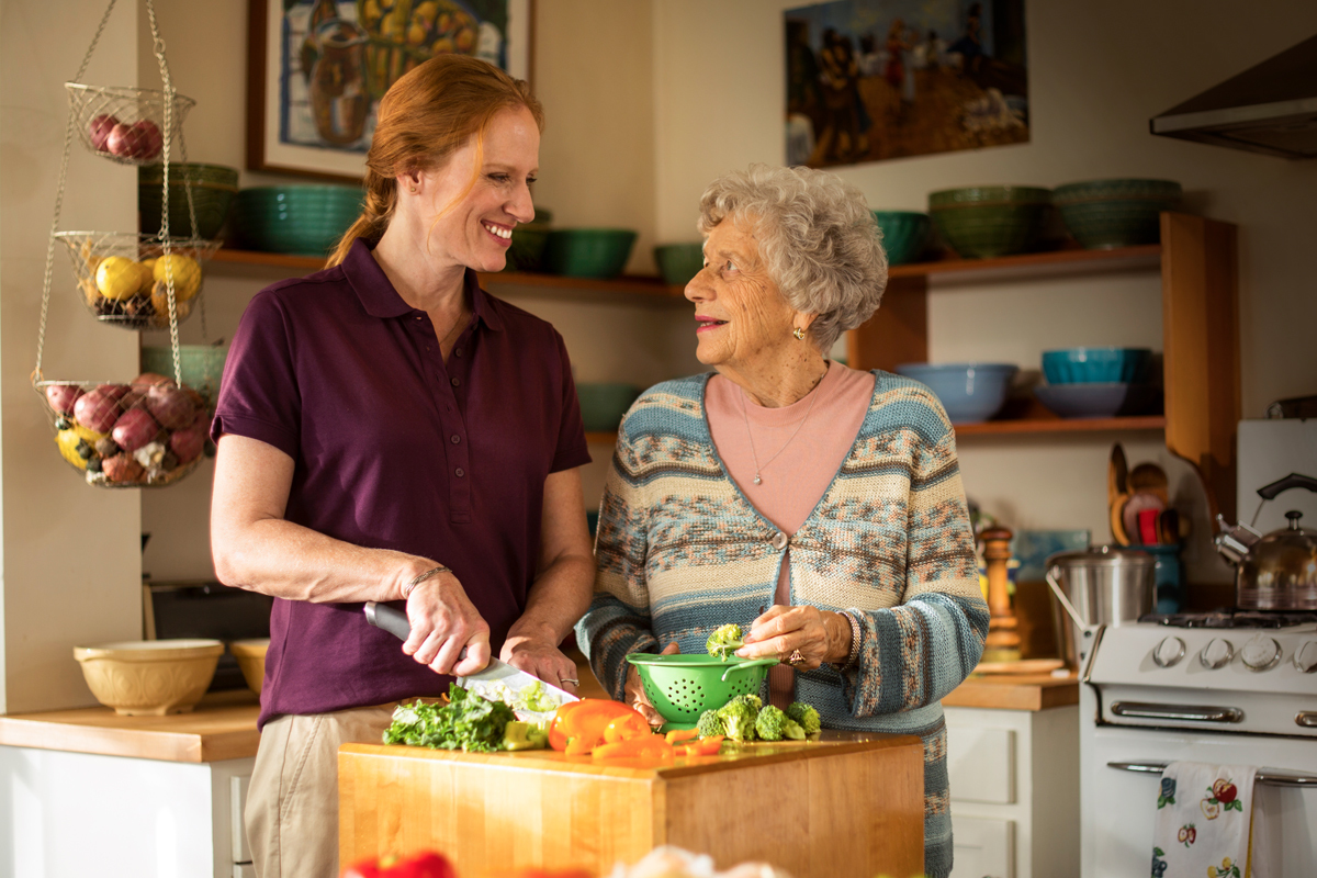 Caregiver and senior cooking in kitchen