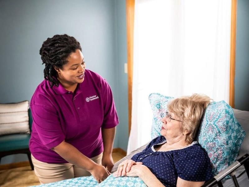 home instead caregiver assisting a senior in bed