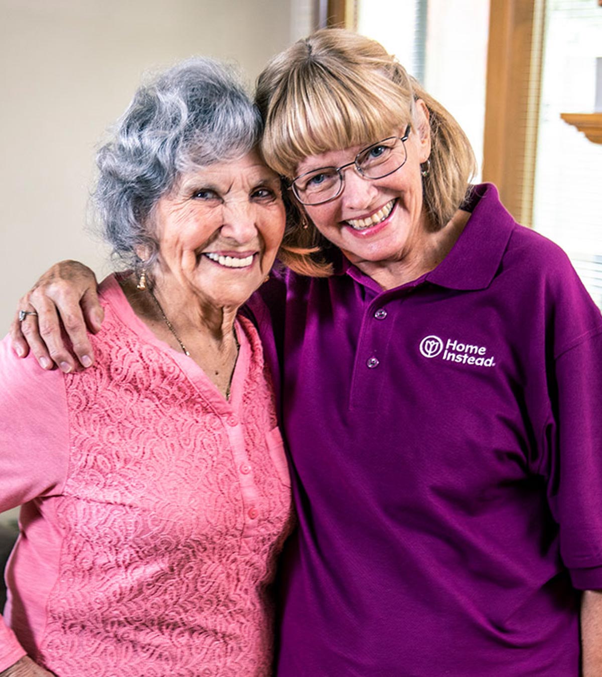 home instead caregiver and senior woman standing and smiling together at home jpg