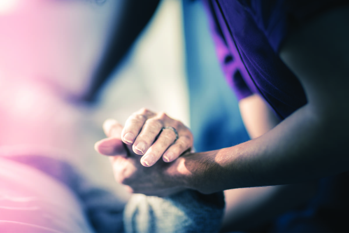 Caregiver and Senior Holding Hands