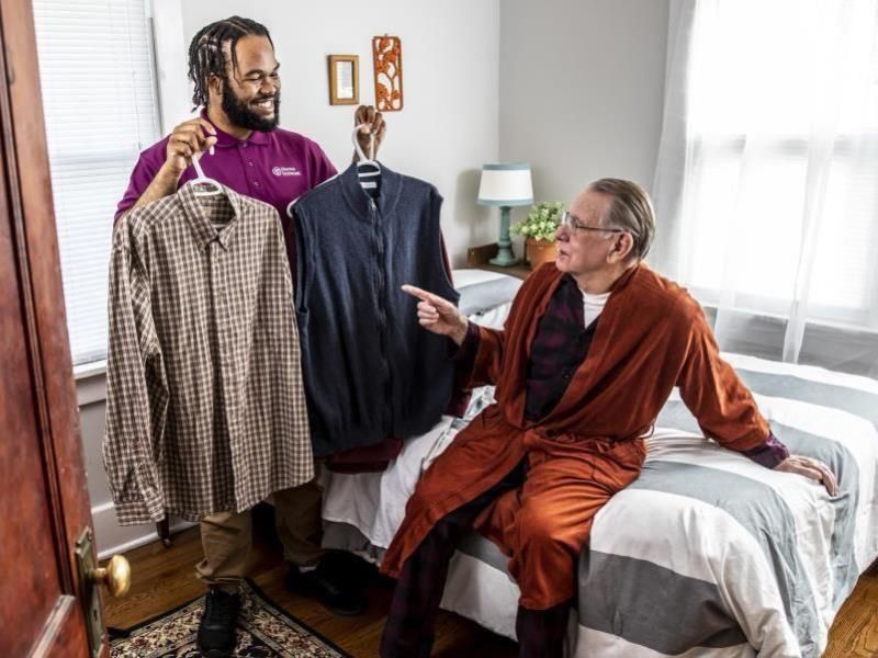 home instead caregiver assisting senior in picking an outfit out