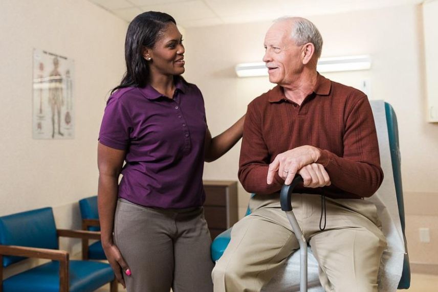 caregiver standing next to a senior in a doctor's office