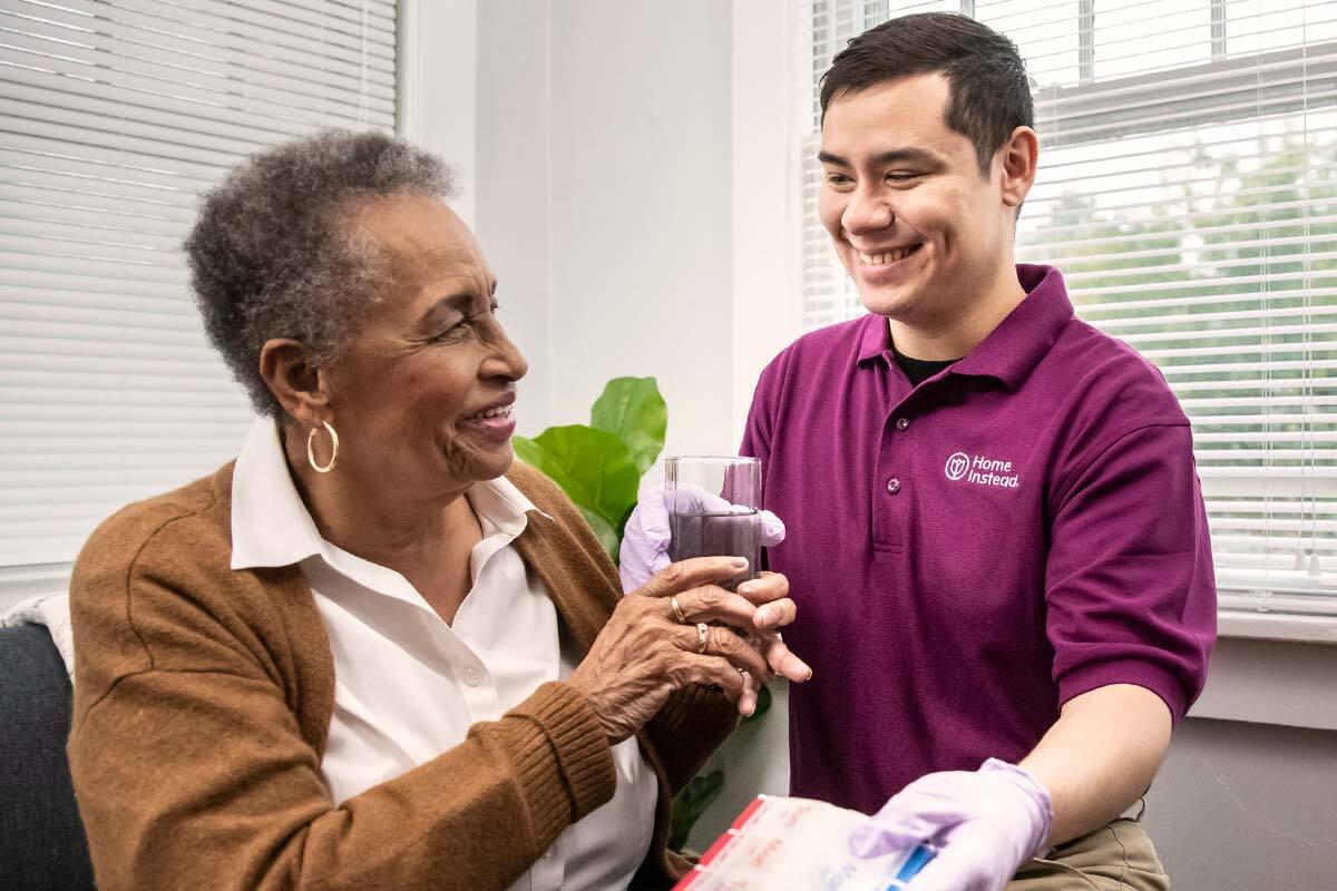 Home Instead Caregiver Provides Senior Woman Medication and Water