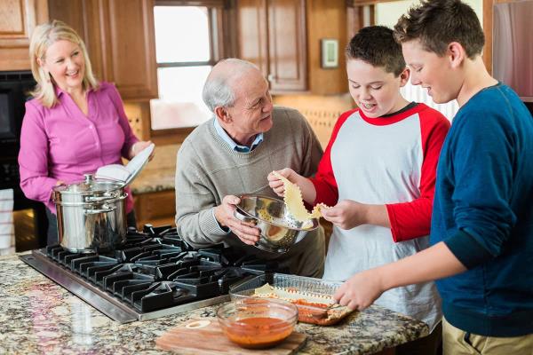 Grandfather, adult daughter and grandkids cooking and living together