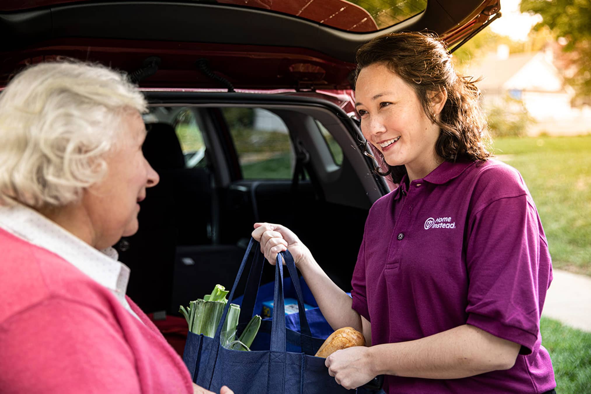 Female Care Professional helping a senior with her bags and assisting with in-home care services.