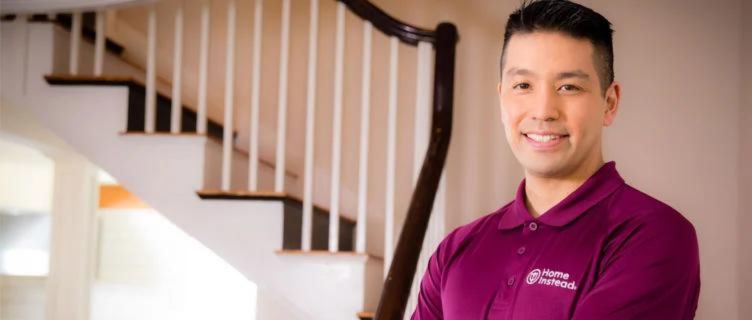 home instead caregiver standing in front of stair case