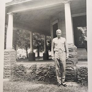 a young solider posing for a photo outside his family's home