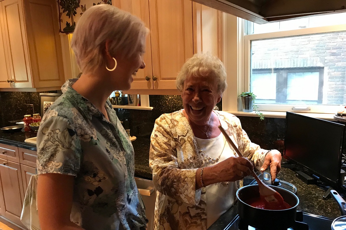 Senior woman cooks meal with caregiver