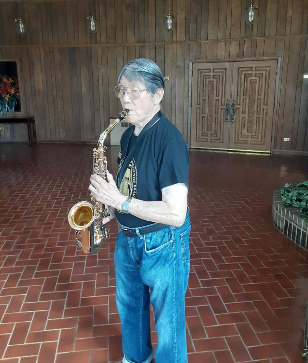 Older Adult standing in a room playing saxophone