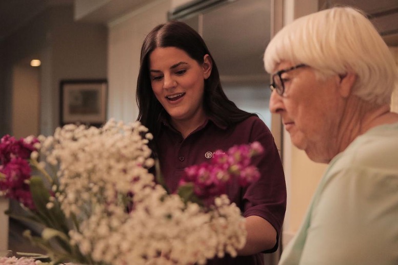 Photo of a Caregiver and an Elder Care client looking at some flowers