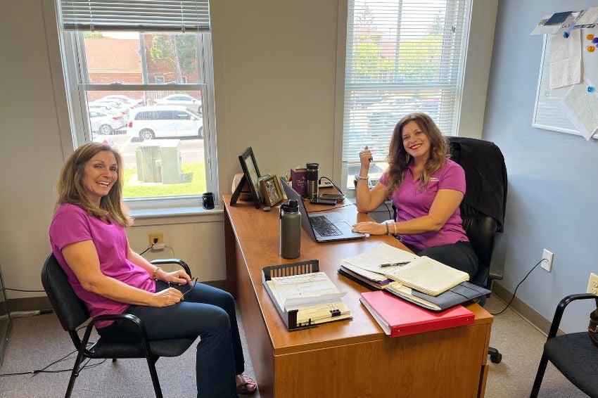 Two Home Instead team members sitting at a desk and smiling