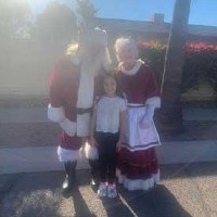 santa and mrs. claus pose with a young kid at a parade