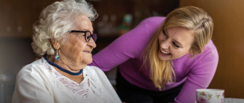 younger woman embracing a senior woman who is smiling