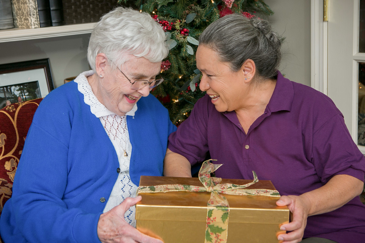 Senior receiving present from caregiver 