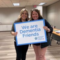 two ladies holding a dementia friends sign