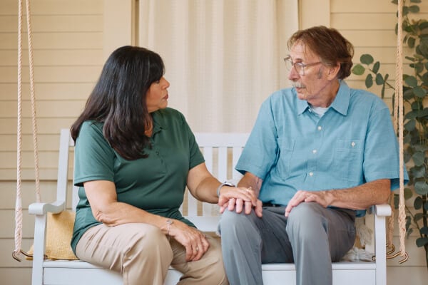 Caregiver reassuringly holds an elderly person’s hand for comfort.
