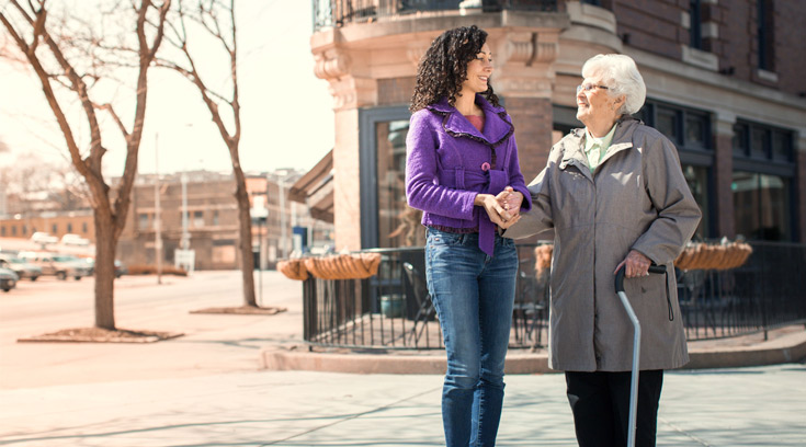 Young woman helping senior woman cross the street