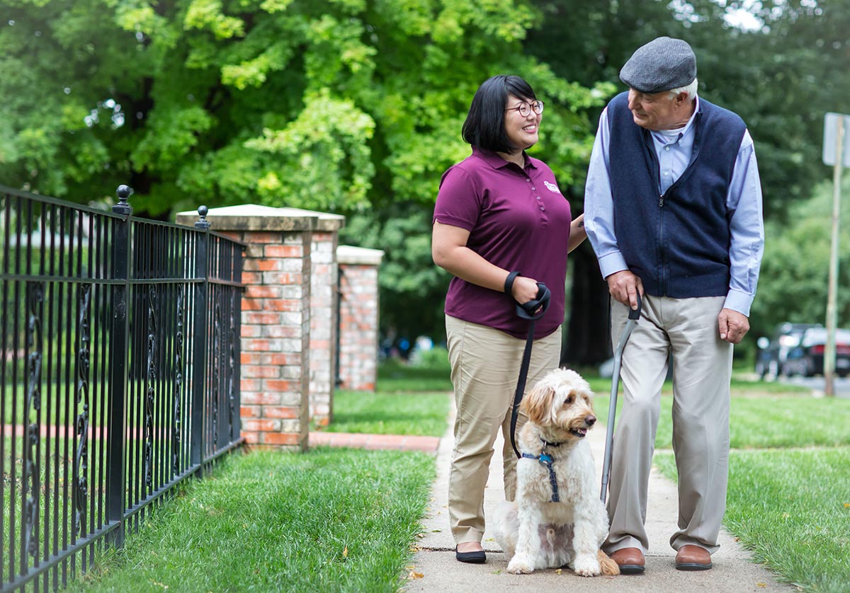 Home Instead Care Pro helping a senior client walk a dog